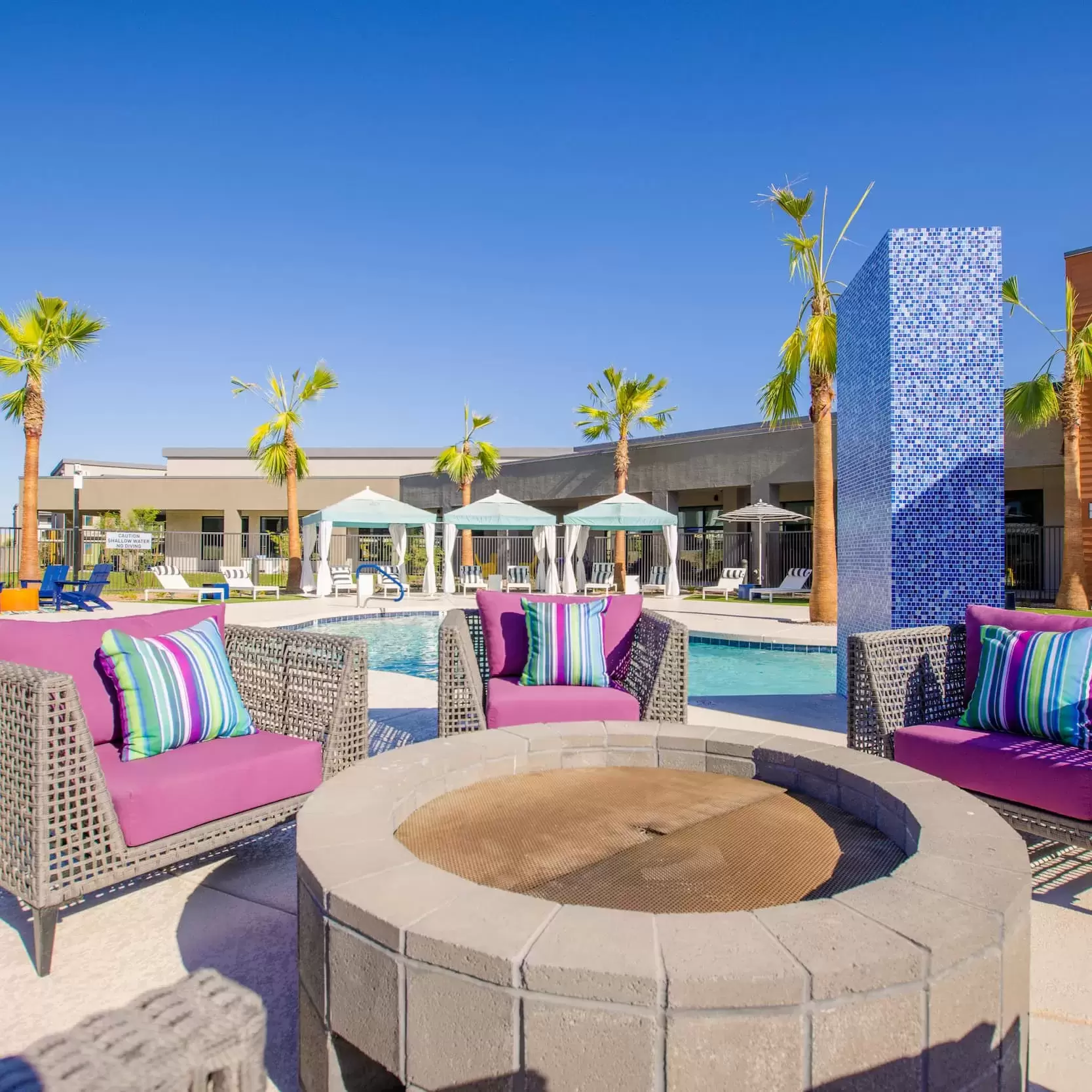 Comfortable chairs surround a firepit on the patio by the pool.